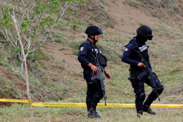 Police guard a plot of land where skulls were found at unmarked graves on the outskirts of Veracruz