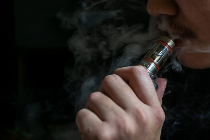 Man with concealed identity smoking a controversial vaping an el