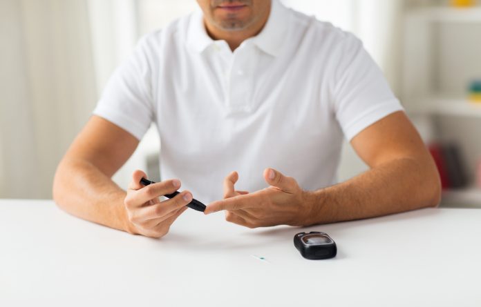 close up of man checking blood sugar by glucometer