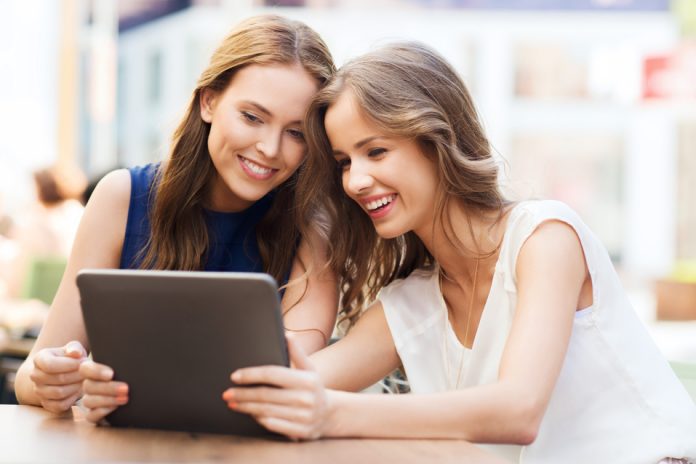 happy young women or teenage girls with tablet pc