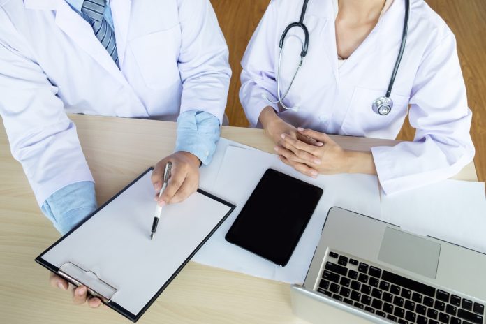 Two doctors discussing patient notes in an office pointing to a