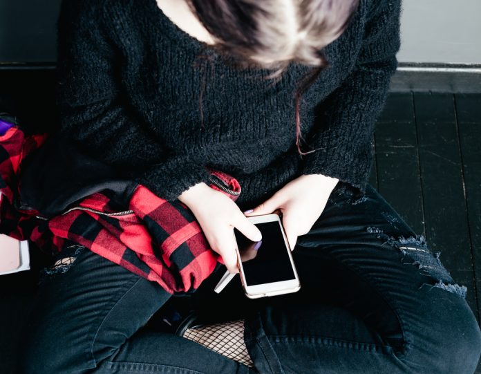 Young alternative girl sitting on the black floor with a school
